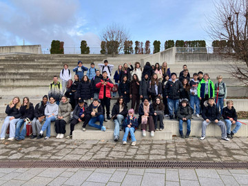 zwei sechste Klassen sitzen auf Steinstufen in der Sonne
