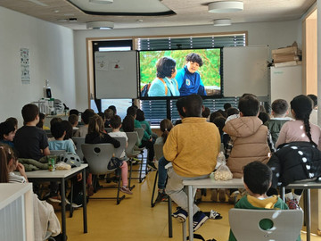 Klassenzimmer, Kinder sitzen in Reihe vor dem Smartboard